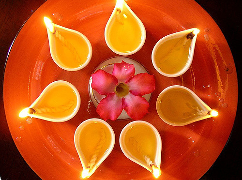 Tealight candles and flower on orange plate.
